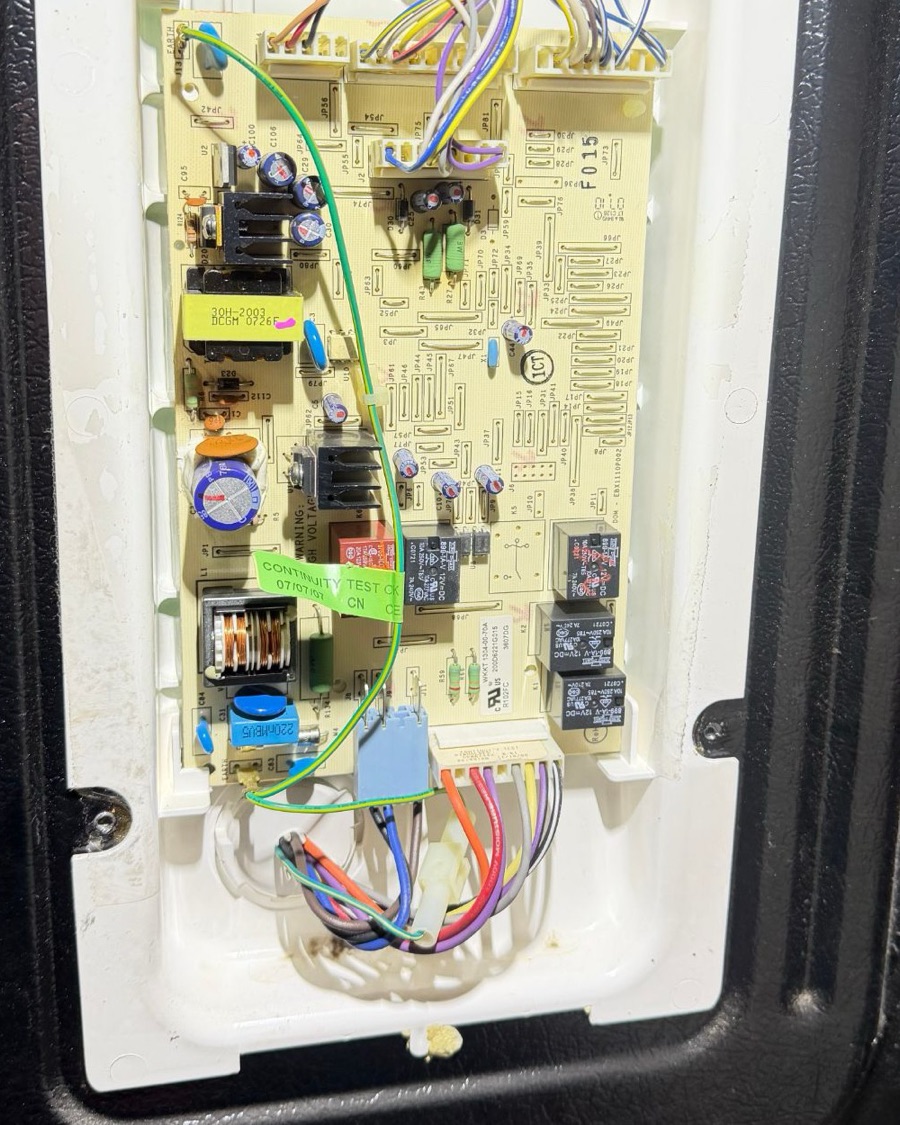 Refrigerator main control board exposed in its housing with the wiring harness connected