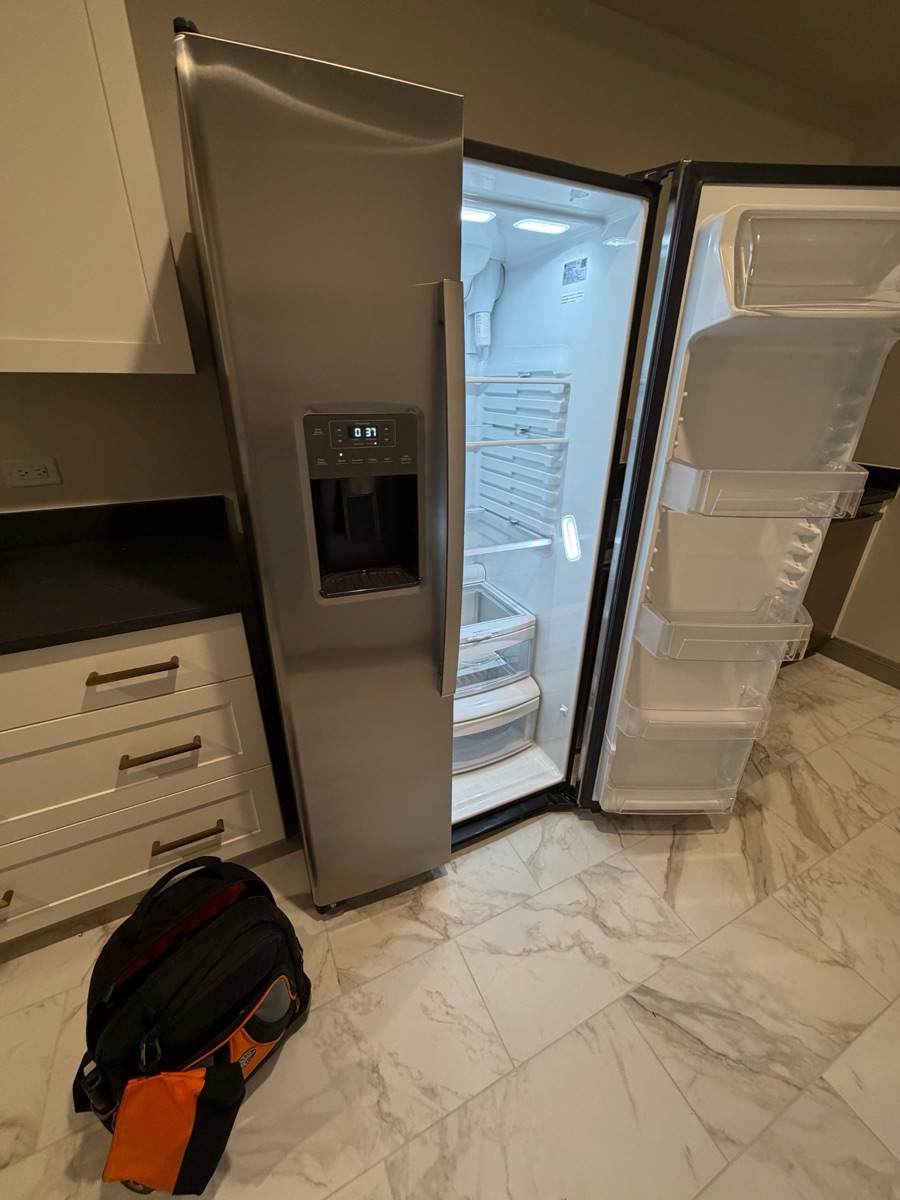 The same refrigerator with the door open, the interior lights on and a temperature showing on the display after the repair