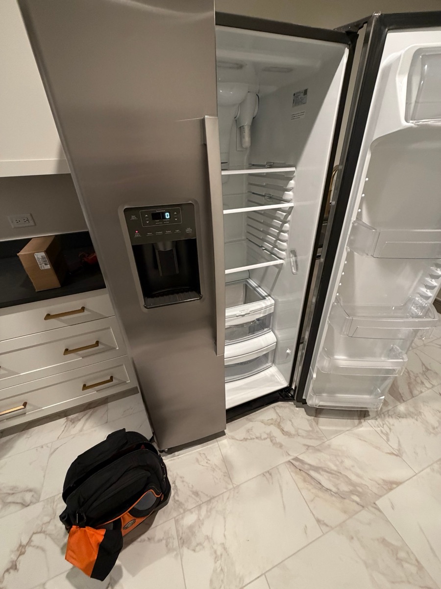 The refrigerator's fresh-food door open with the interior lights off and the display showing zero