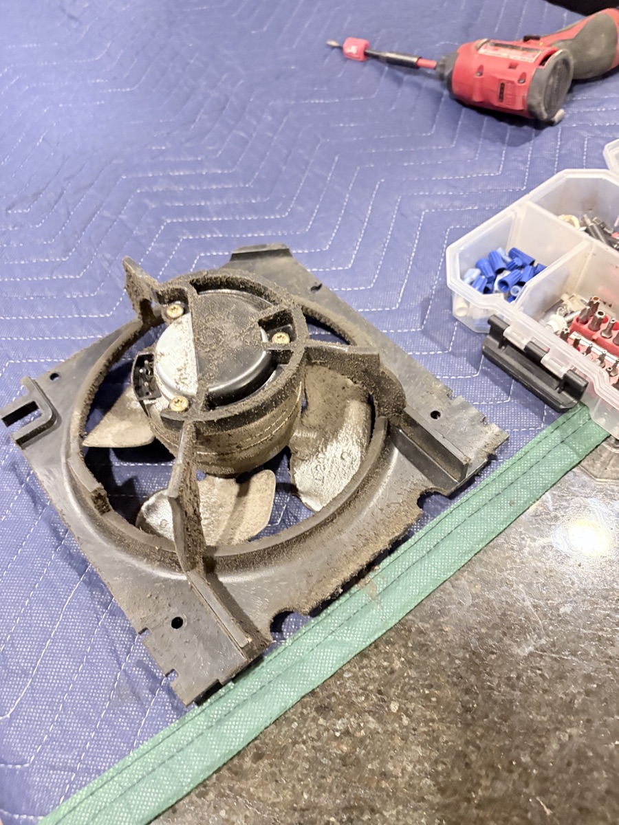 Removed condenser fan motor assembly from a built-in refrigerator, on a moving blanket with a drill and parts organizer